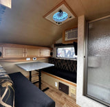 Cozy RV rental interior with dinette, cabinets, AC, and shower stall. Perfect compact living space for travel.