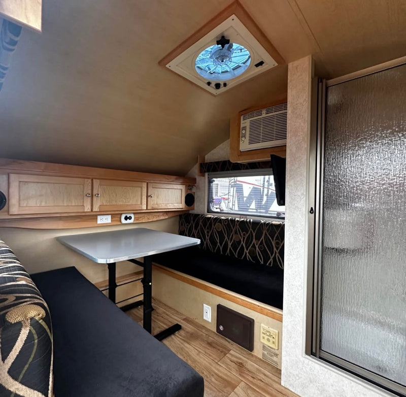 Cozy RV rental interior with dinette, cabinets, AC, and shower stall. Perfect compact living space for travel. — photo 10