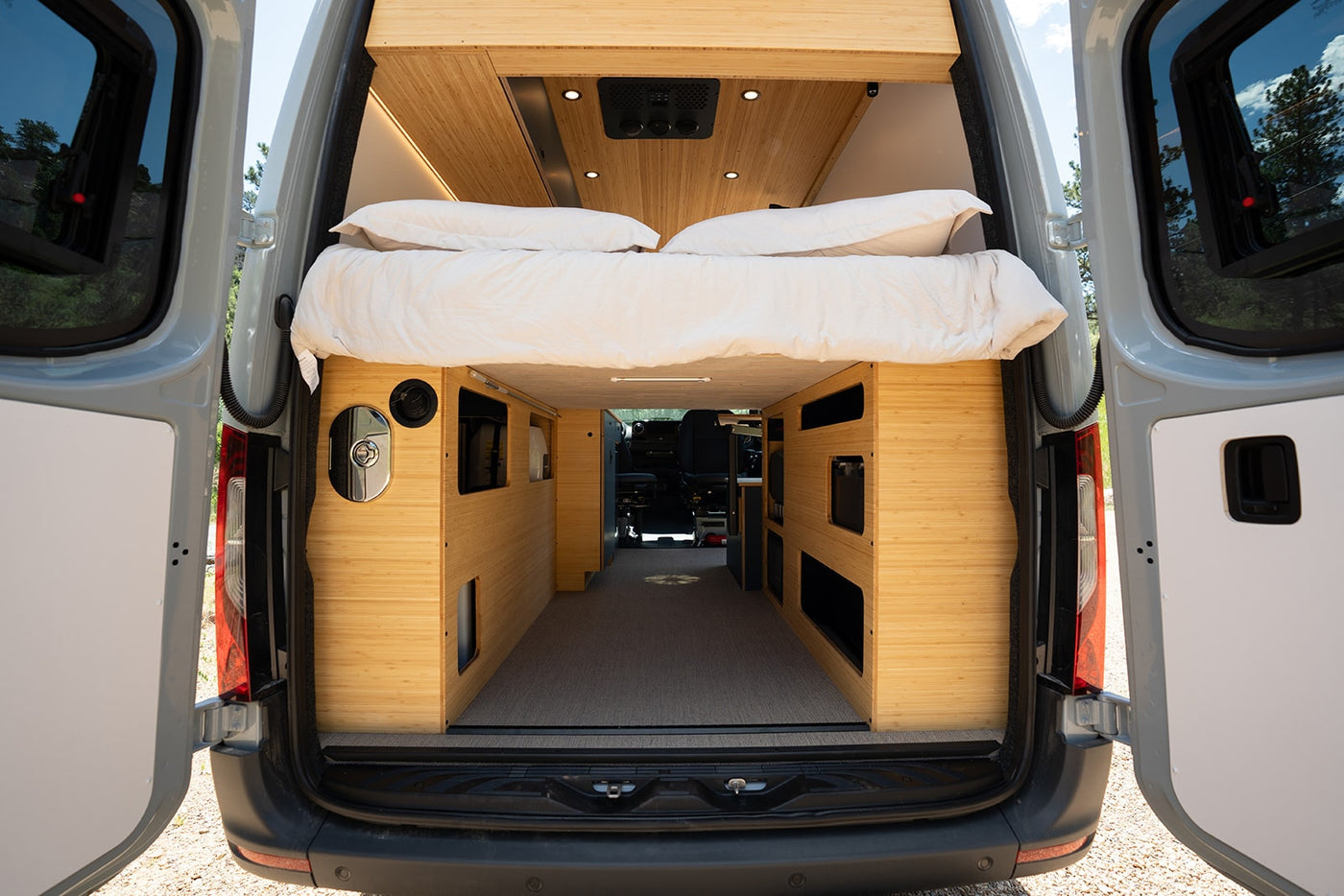 Step inside this modern RV rental's converted van. Features a comfy bed, bamboo storage, and open rear doors. — photo 19