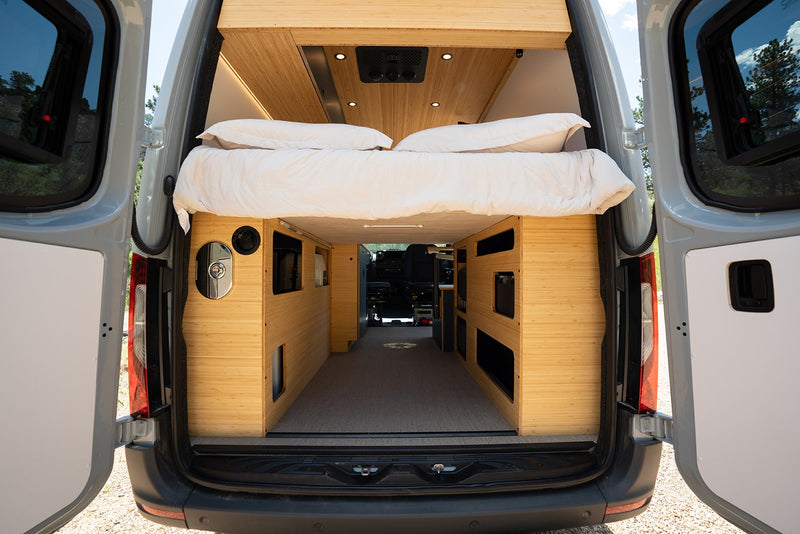 Step inside this modern RV rental's converted van. Features a comfy bed, bamboo storage, and open rear doors. — photo 19