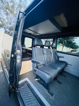 Inside an RV rental van, featuring three passenger seats, a rear sleeping platform, and an open side door for easy access.