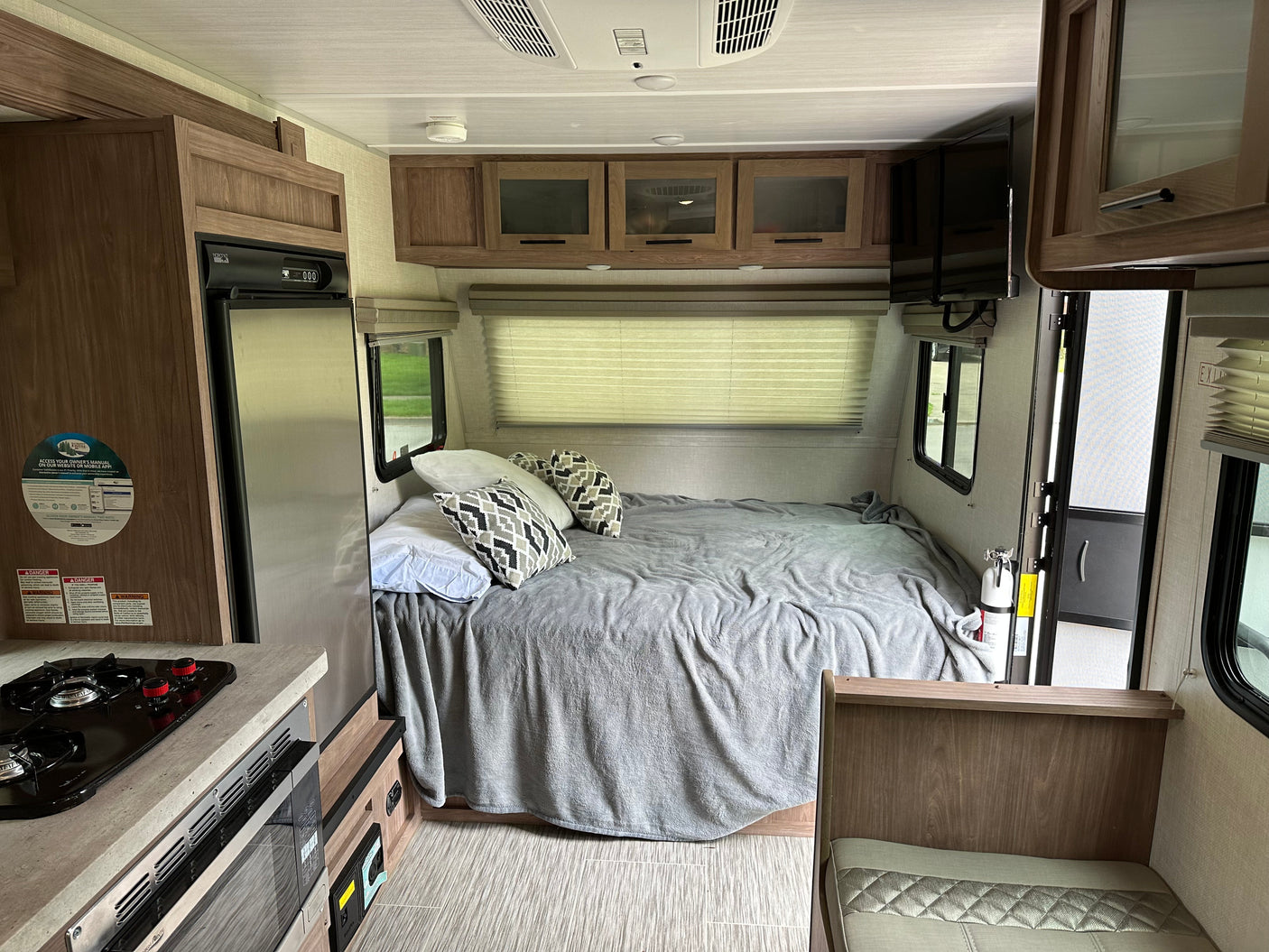 Inside an RV rental, featuring a comfortable bed, compact kitchen, overhead cabinets, and a television, ready for your trip.