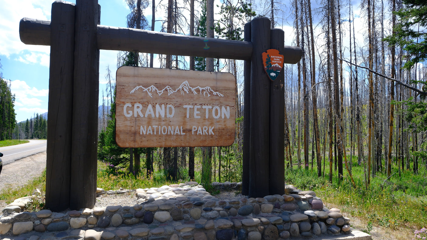 Grand Teton National Park entrance sign. Start your rv rental journey to this stunning park, surrounded by trees.