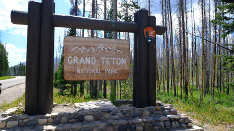 Grand Teton National Park entrance sign. Start your rv rental journey to this stunning park, surrounded by trees.