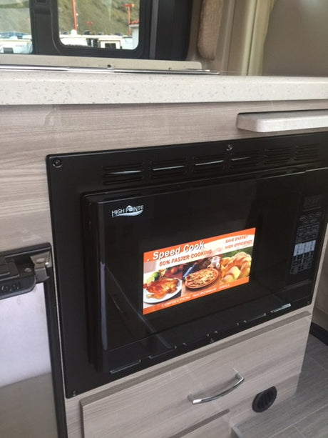 Inside an rv rental: A compact kitchen area featuring a High Pointe microwave, countertop, and wood-look cabinetry.