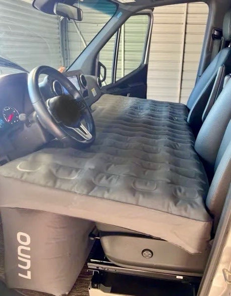 Front cab of an RV rental van with a Luno inflatable mattress for comfortable camping & road trips.