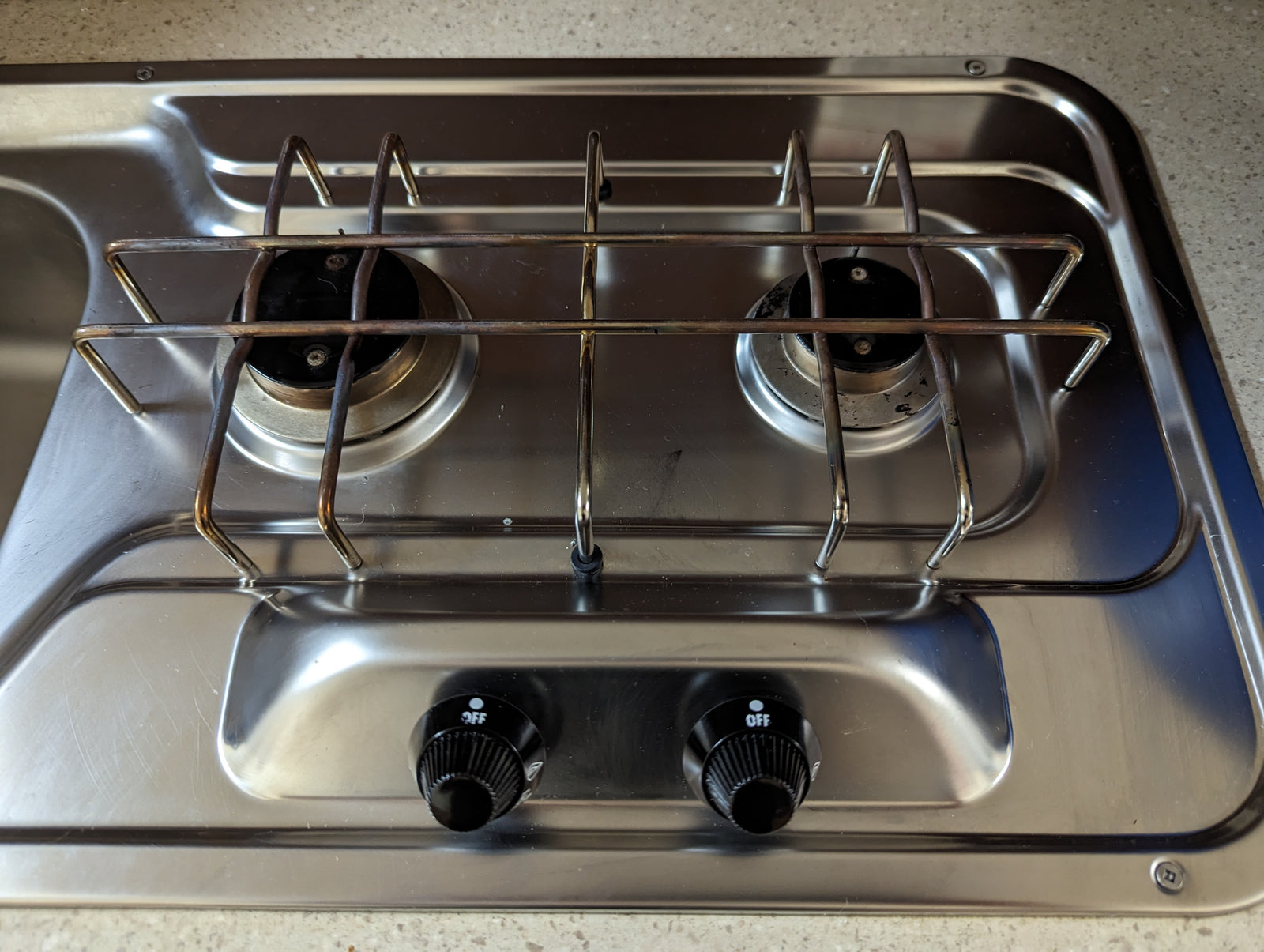 RV rental's compact stainless steel two-burner cooktop with integrated sink, ready for travel adventures.