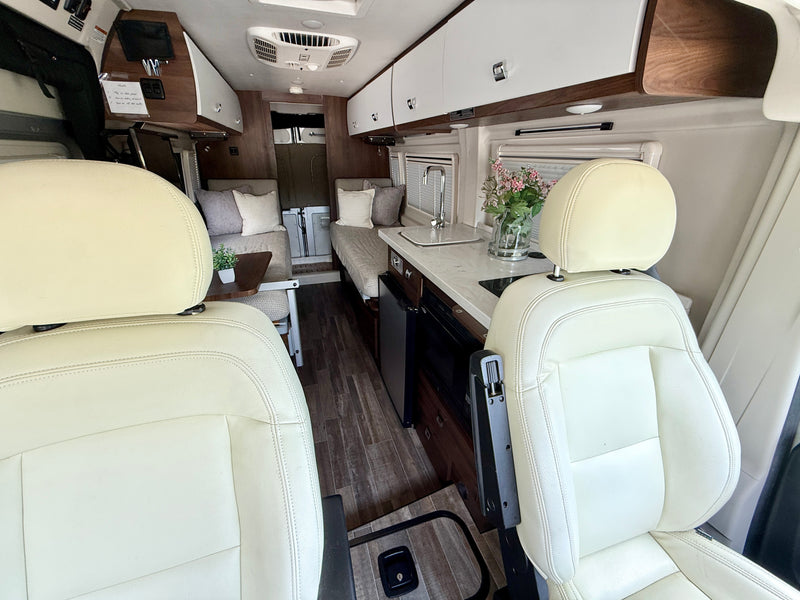 View from the front seats of a modern RV rental, featuring a compact kitchen, cozy seating, and clean interior. — photo 12