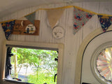 Cozy RV rental interior with decorative bunting, "enjoy the journey" sign, and window view of nature.