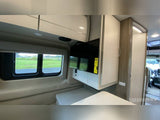 Inside this RV rental, find a compact living space with large windows, wall-mounted TV, and cozy bench seating.
