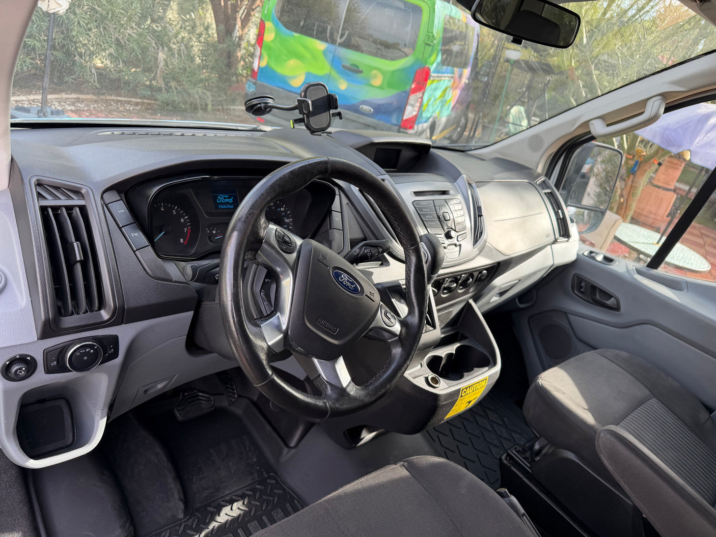Dashboard of a Ford Transit RV rental van, featuring steering wheel, odometer (194k miles), and phone mount.