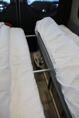 Two beds with white bedding in an RV rental, showcasing efficient interior space and accessible storage.