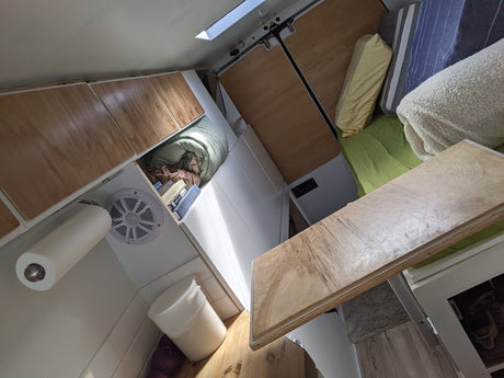 RV rental interior showcasing smart storage, cozy bed, and practical kitchenette features within a compact van.
