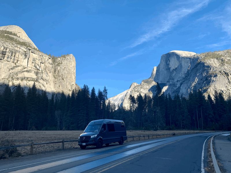 An RV rental camper van rests by the road in stunning Yosemite Valley, with Half Dome and other iconic granite peaks under a clear sky. — photo 17