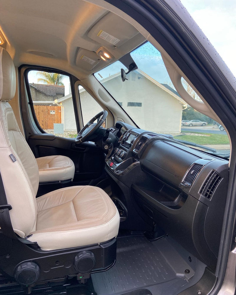  parked on asphalt with dry hills under a clear blue sky.|Enjoy an RV rental: a dark grey camper van parked by a sunny beach and ocean view. Ideal for road trip adventures!|Spacious RV rental cabin: Light leather front seats — photo 3