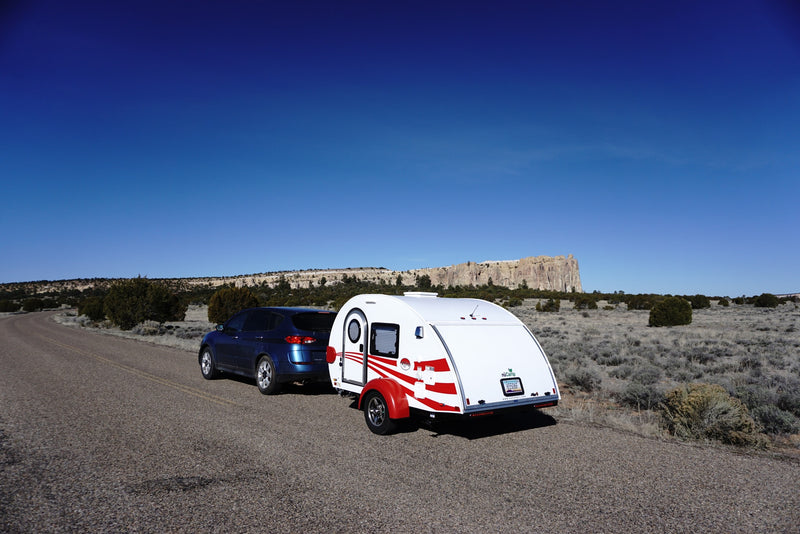 Blue SUV with RV rental teardrop camper parked on a desert road under clear blue skies, with rock formations in background. — photo 7