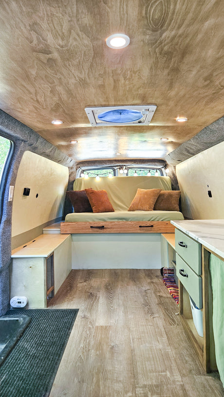 Cozy RV rental interior featuring a wood ceiling, recessed lights, comfy sofa, and practical built-in storage.