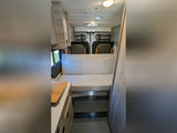 Spacious RV rental interior with bench seat, kitchen counter, and rear lounge area. Perfect for a camper van adventure!