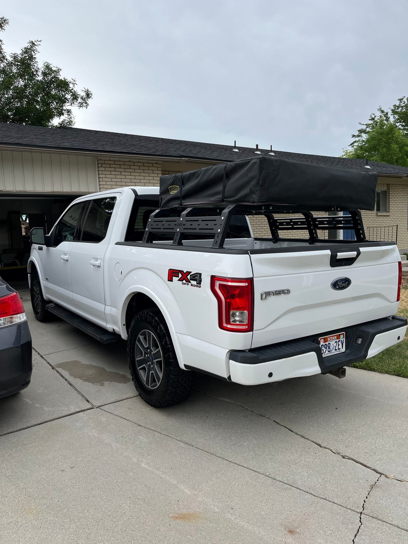 White Ford F-150 pickup with overland rooftop tent, ready for an RV rental adventure in the driveway. — photo 11