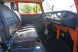 Interior of a vintage RV rental: front seats, dash, and manual shift in the driver's cabin. Ready for adventure!