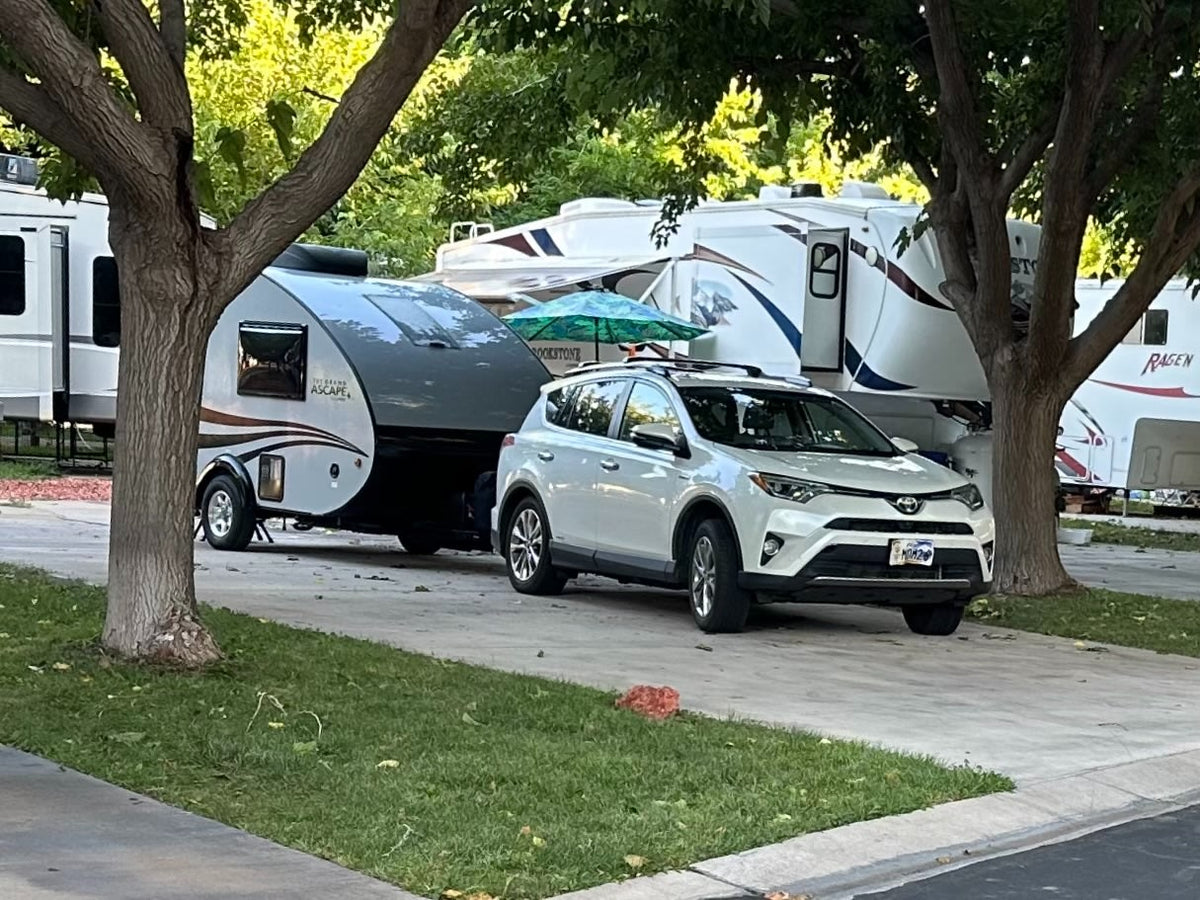 White SUV towing a teardrop RV — photo 1