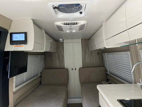 Spacious RV rental interior featuring twin beds, overhead storage, and kitchen. Ideal for comfortable road trip adventures.