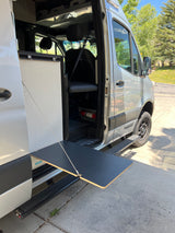 Silver camper van, ideal for rv rental adventures. Side door open, revealing interior & an extendable outdoor table.
