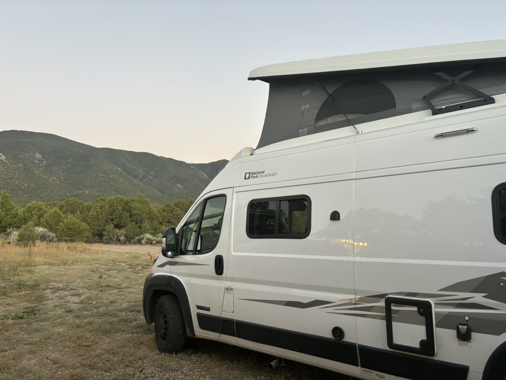 White pop-top RV rental in a mountain landscape