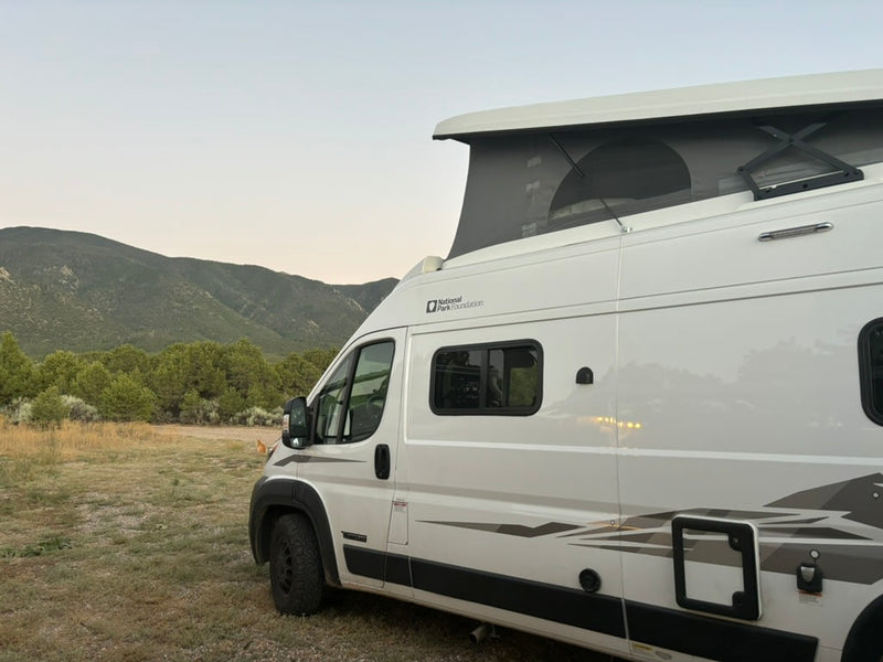 White pop-top RV rental in a mountain landscape — photo 1