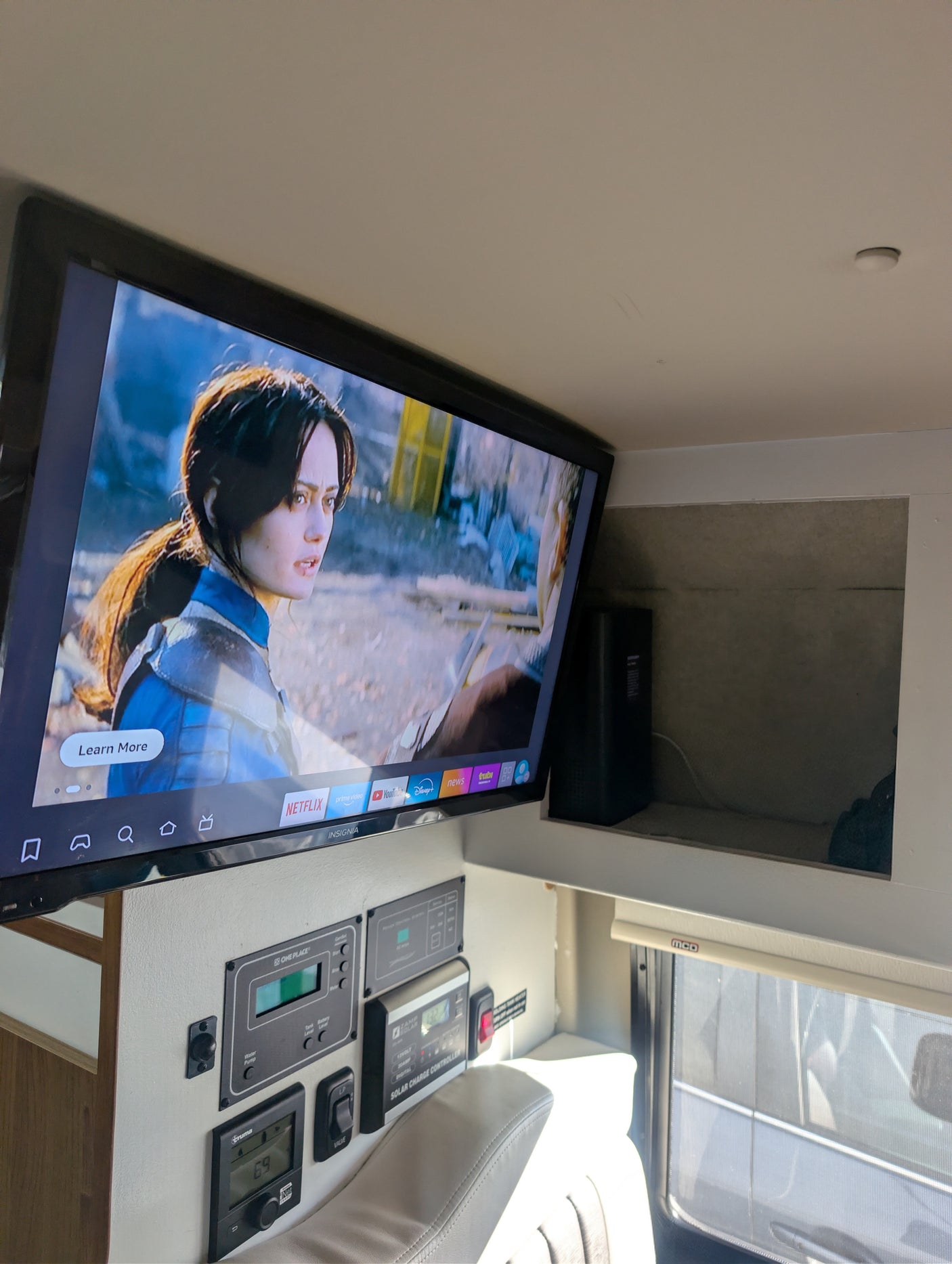 This RV rental's interior features a TV playing Netflix, with detailed control panels for water, solar, and heating below it.