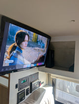 This RV rental's interior features a TV playing Netflix, with detailed control panels for water, solar, and heating below it.