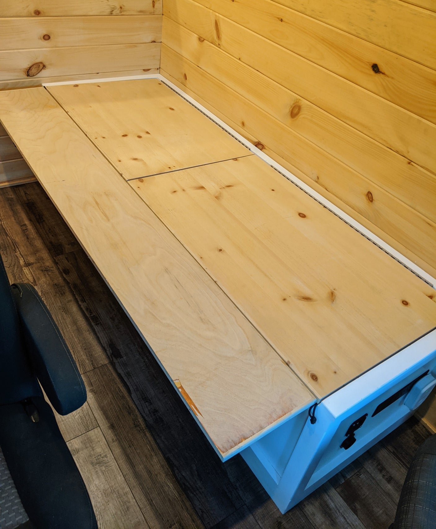 RV rental with a versatile wooden platform that converts for seating or sleeping, featuring plank walls and a durable floor.