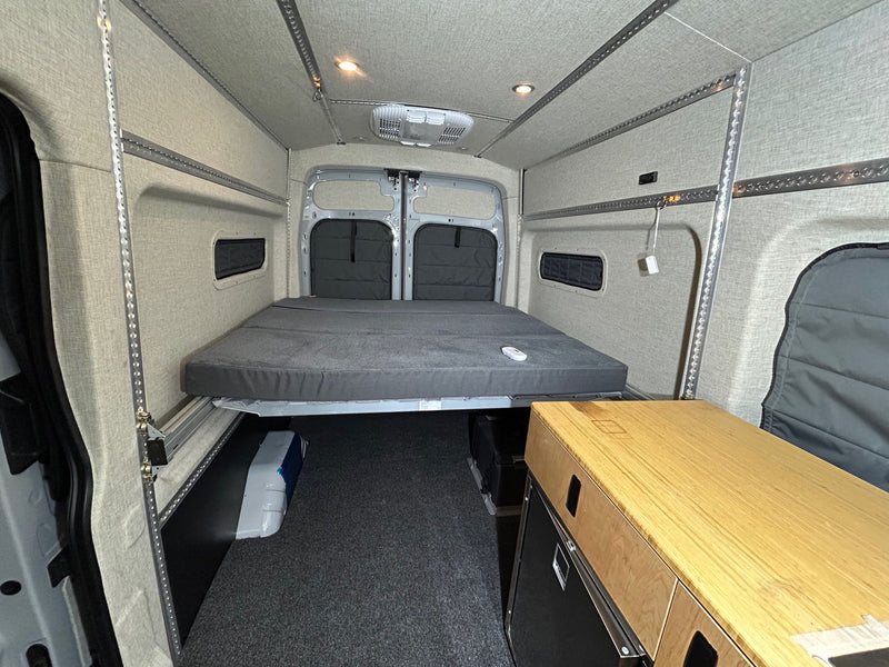  and custom wood storage cabinets.|Converted van interior: a cozy RV rental for adventure. Features bed — photo 7
