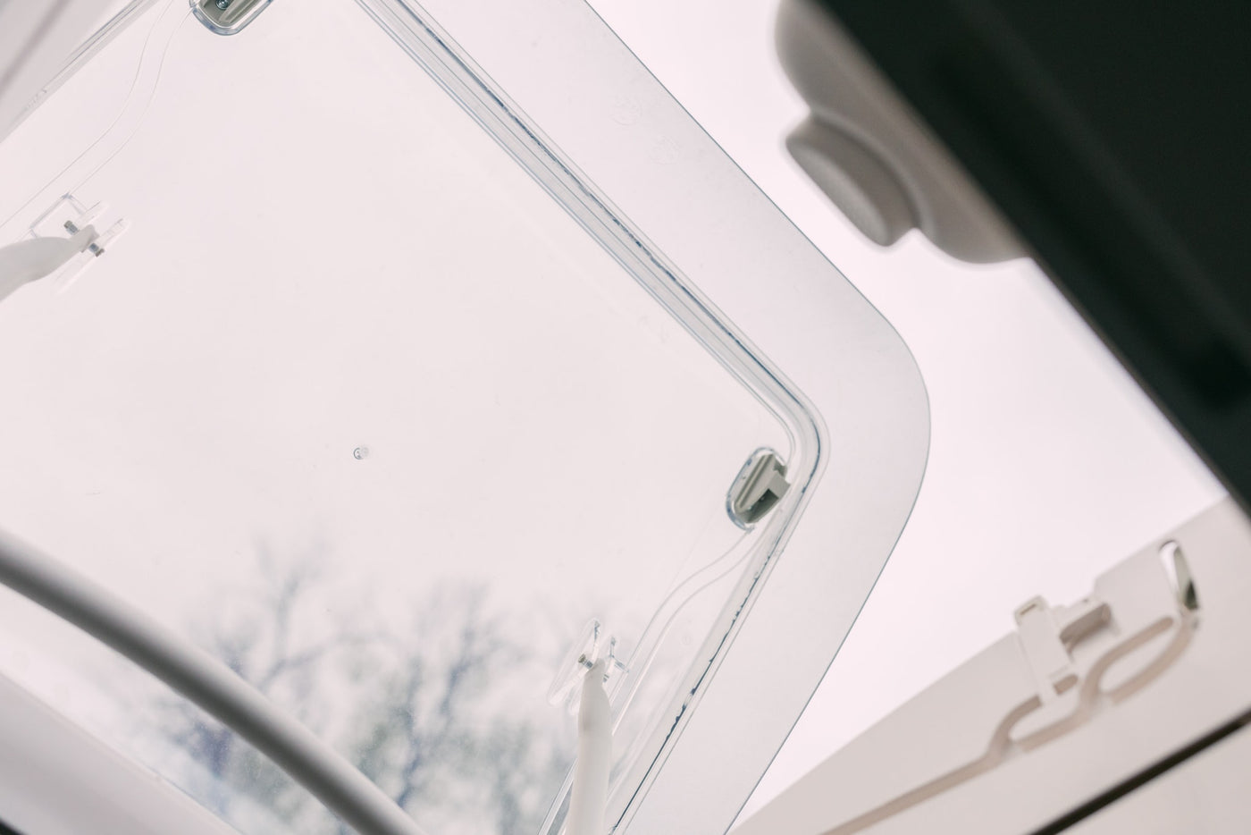An open RV skylight provides natural light and a view of trees from inside an RV rental. — photo 15