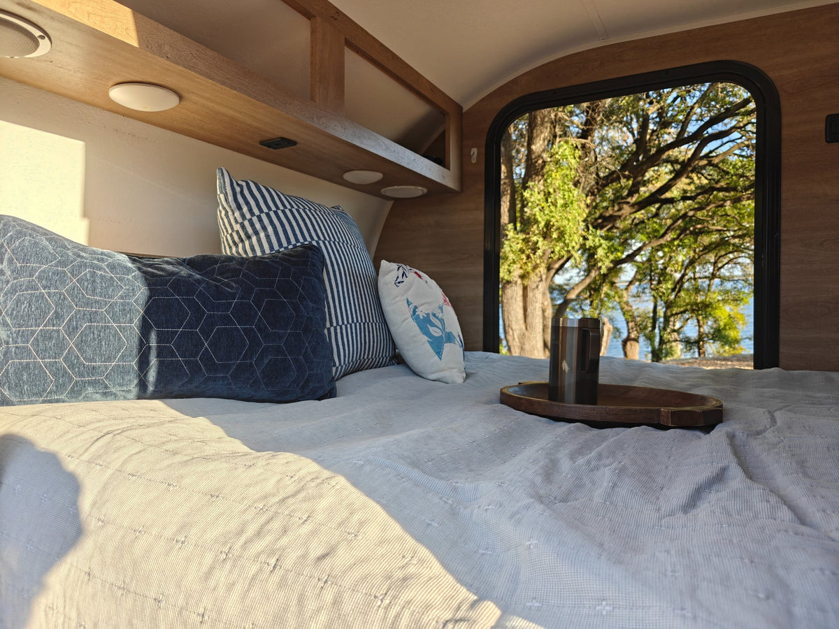  parked on a sunny gravel lot amidst trees.|Scenic RV rental: a vibrant teardrop trailer with an open outdoor kitchen — photo 11