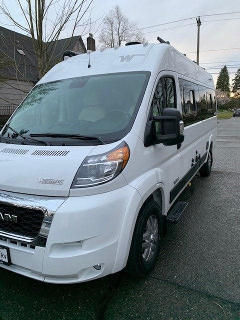 Modern white Winnebago Travato camper van, an RV rental, parked outdoors on a street. — photo 16