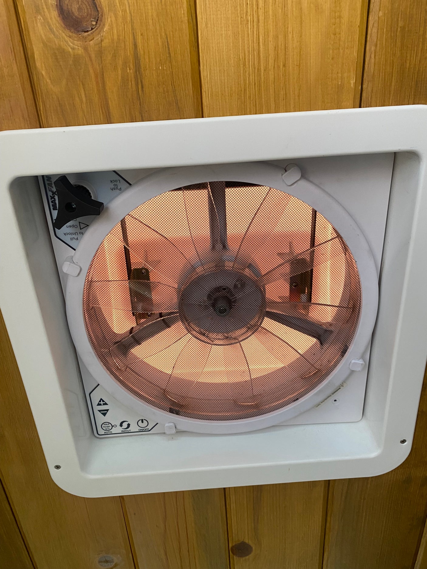 Inside an RV rental: a MaxxAir roof vent fan with its control panel and mesh screen, installed in a wooden ceiling.