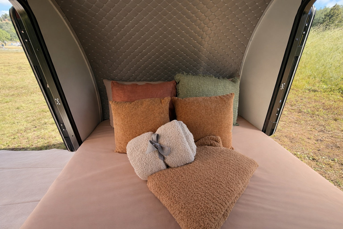 Cozy rv rental bed with soft pillows and blankets, offering a serene view of nature. Ideal for a comfortable getaway.