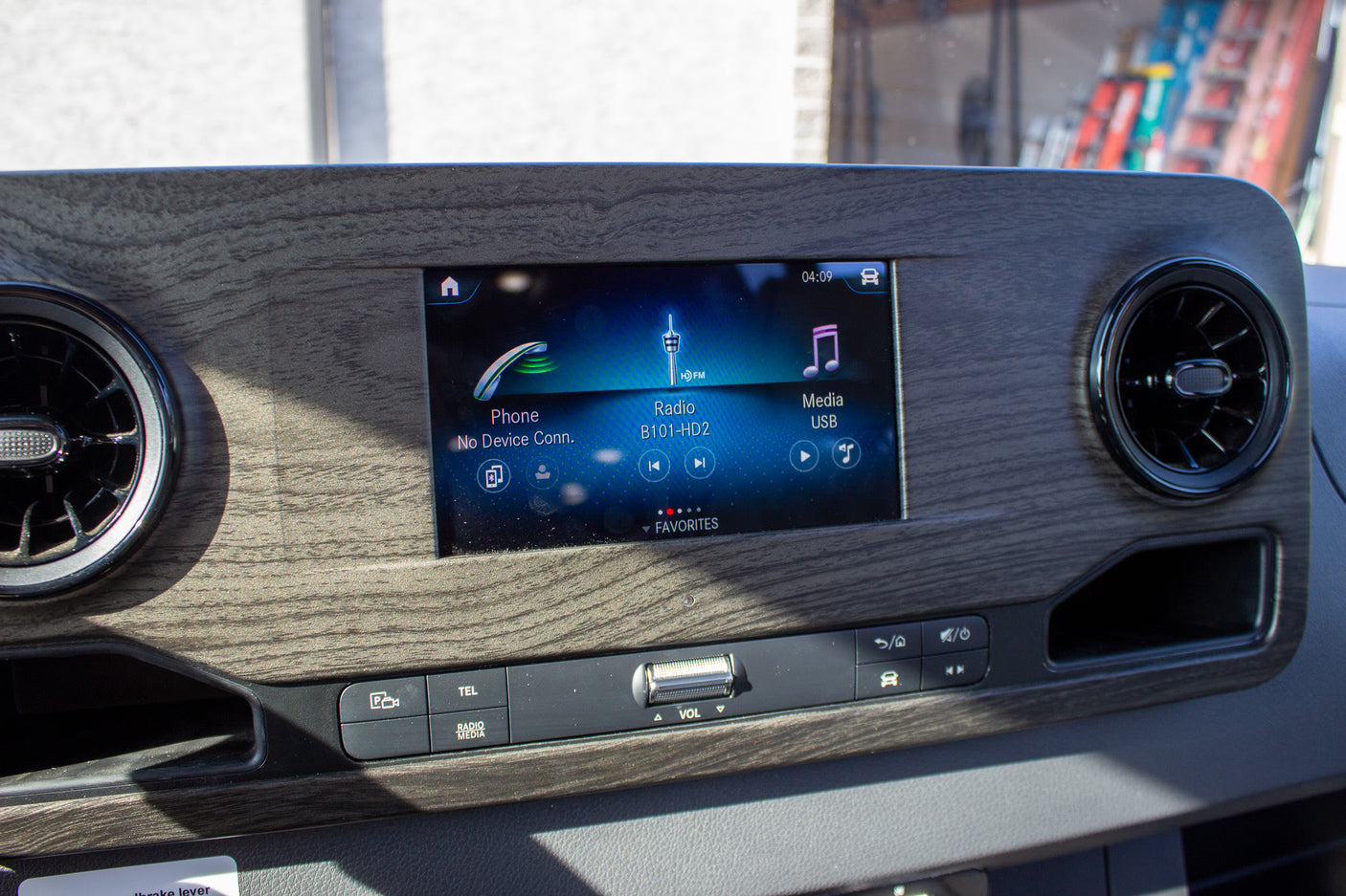RV rental interior: Modern dashboard infotainment system with touchscreen display for radio, phone, and media. Includes clear audio controls.