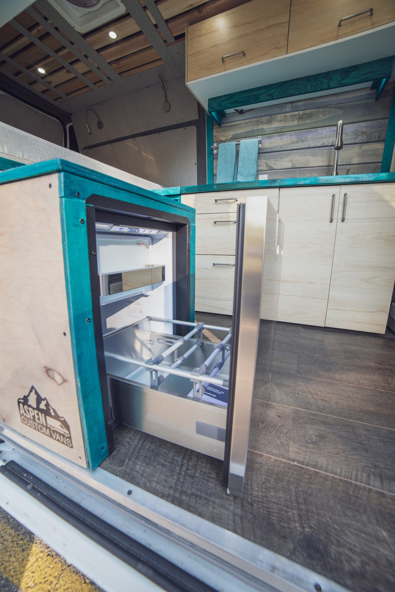 Step inside this custom RV rental, featuring a modern kitchen with a pull-out fridge, light wood cabinets, and teal accents. — photo 3