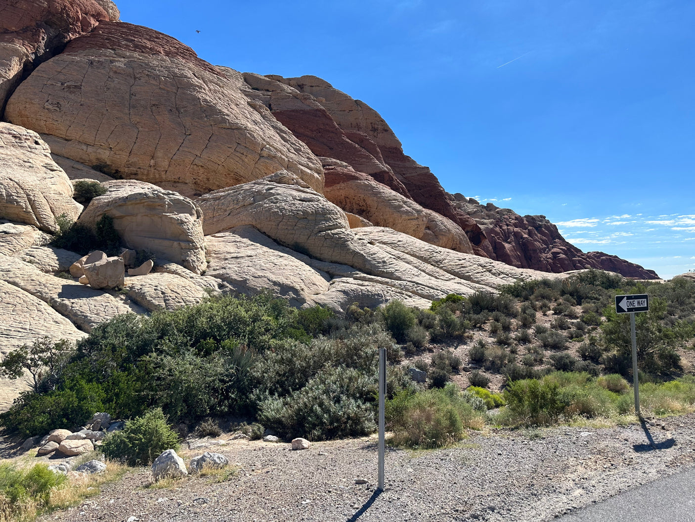 Majestic layered tan and red rock formations amidst desert flora. A scenic route perfect for your RV rental adventure. One-way travel.