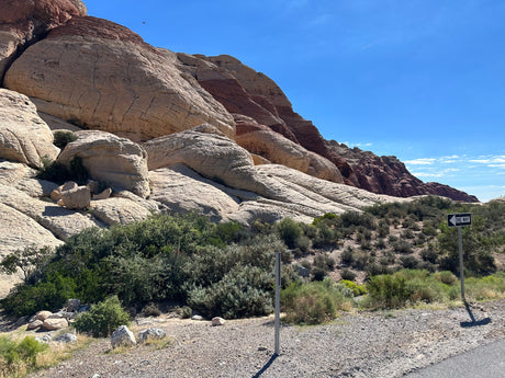 Majestic layered tan and red rock formations amidst desert flora. A scenic route perfect for your RV rental adventure. One-way travel.