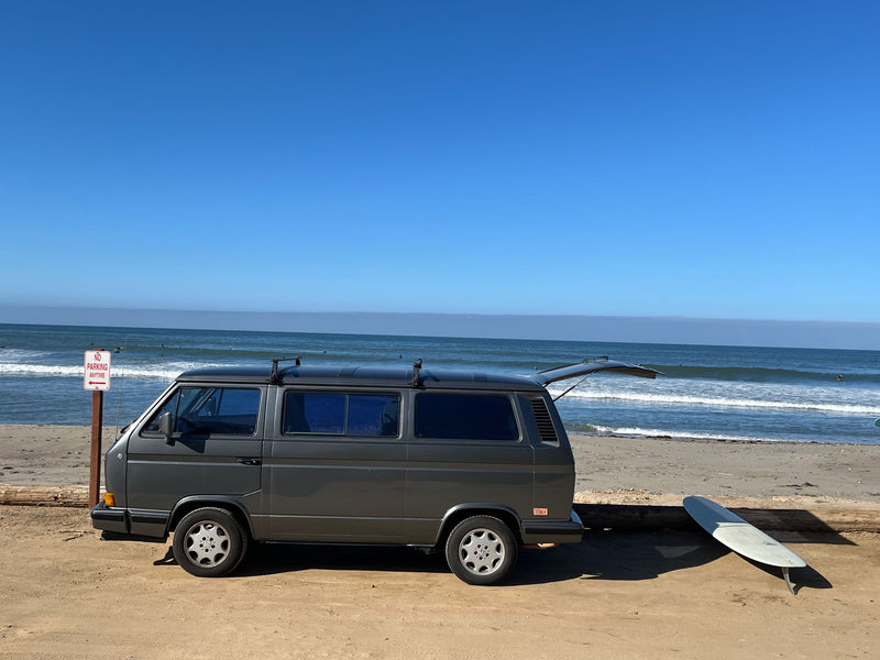  and beachside cooking with ocean views.|Front view of a gray VW Vanagon camper van parked at a scenic ocean-side campsite. Ideal RV rental for your next adventure.|Open side of a gray RV rental van — photo 2