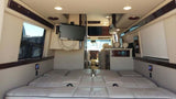 Luxurious RV rental interior shows a spacious bed, multiple TVs, and a clear view to the front cabin for comfortable travel.