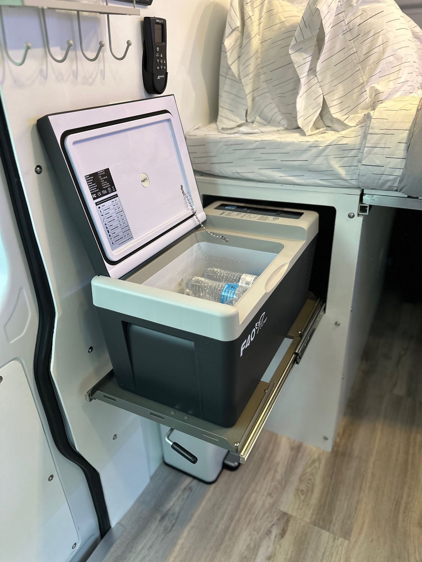 RV rental: Portable fridge on a pull-out slide holds water bottles. Compact, convenient interior with overhead bed. Ideal for travel.