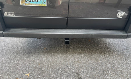 An RV rental's rear shows a tow hitch and bumper sensors, ready for adventure.