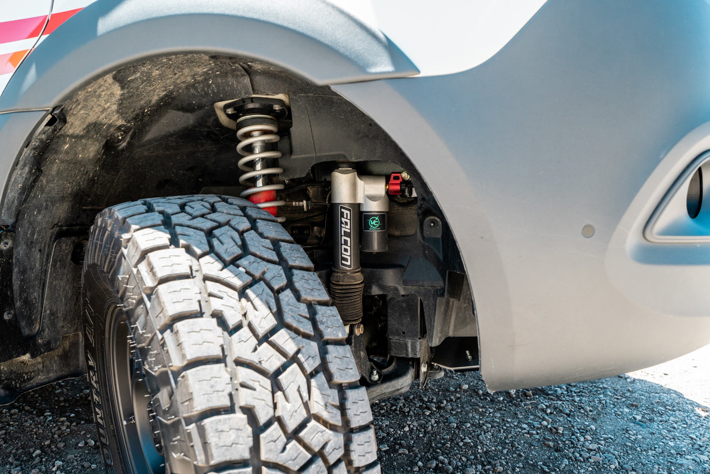 Upgraded suspension and off-road tire on an RV rental. A Falcon shock absorber and coil spring are visible in the wheel well.