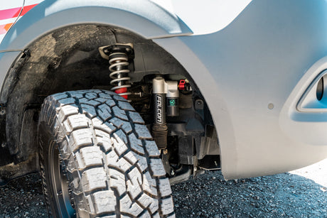 Upgraded suspension and off-road tire on an RV rental. A Falcon shock absorber and coil spring are visible in the wheel well.