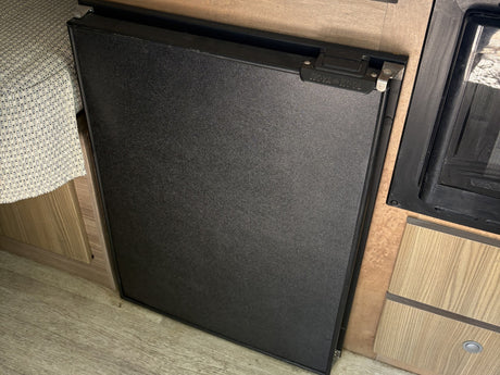Nova Kool compact refrigerator in an RV rental, integrated into the kitchen area with cabinetry and seating.