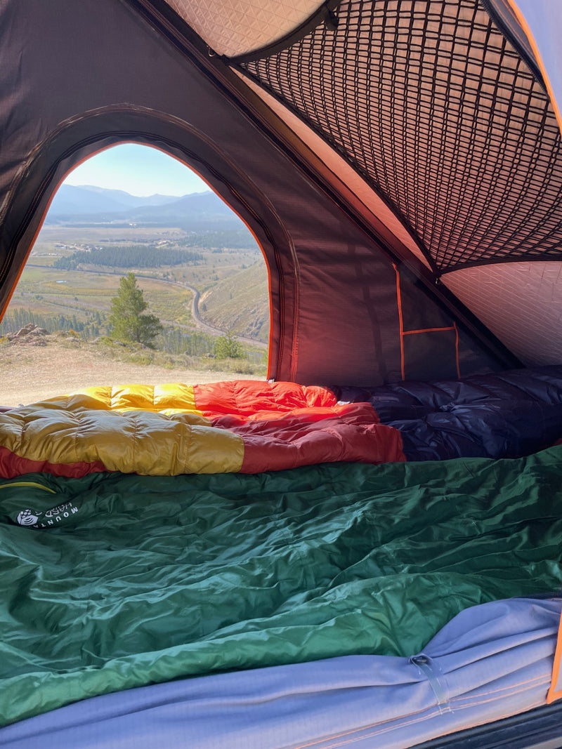 Cozy tent bed with vibrant sleeping bags looking out at a stunning valley view. RV rental adventure! — photo 7